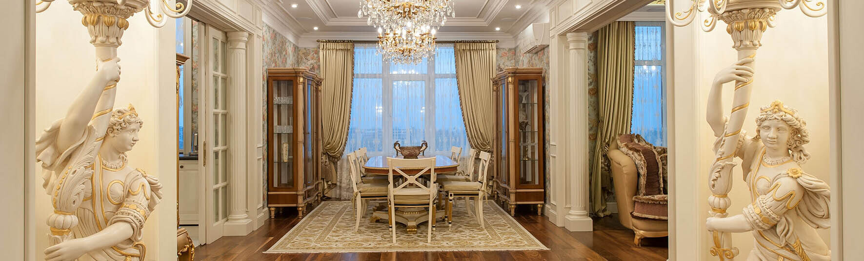 Elegant Neoclassicism — formal dining room framed by sculpted columns beneath a crystal chandelier