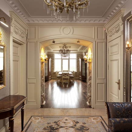 Archway framing a formal dining room, flanked by wall sconces and carved paneling