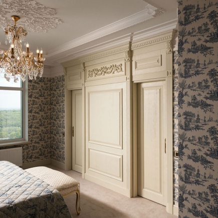 Bedroom with carved wood sliding closet doors and toile wallpaper