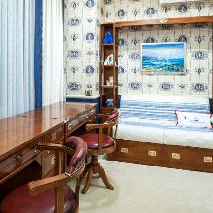 Built-in daybed nook with sailboat artwork and nautical-print wallpaper