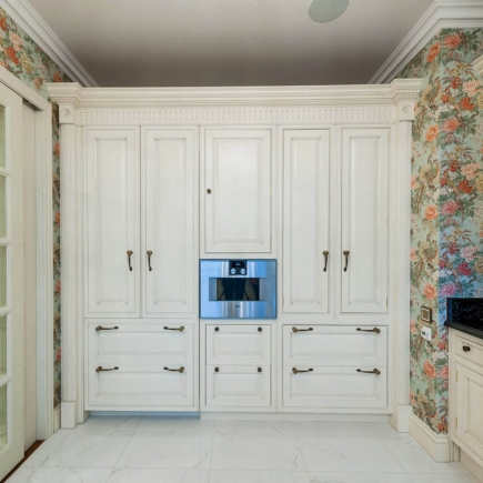 Built-in kitchen wall cabinetry with a built-in oven flanked by floral wallpaper