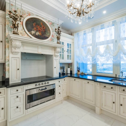 Classic kitchen with carved wood range hood, floral mural, and crystal chandelier