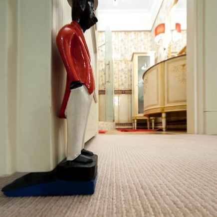 Decorative jockey-figure doorstop beside a bedroom doorway with a bathroom visible beyond