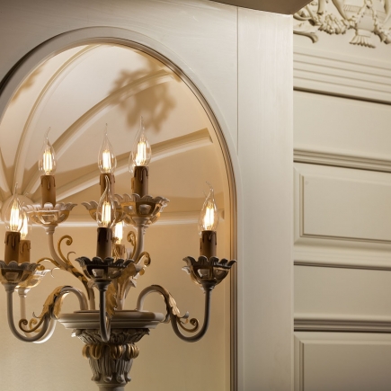 Detail of an antique brass candelabra beside an arched mirror