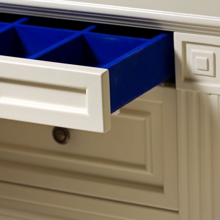 Detail of an open drawer with blue velvet dividers in a walk-in closet
