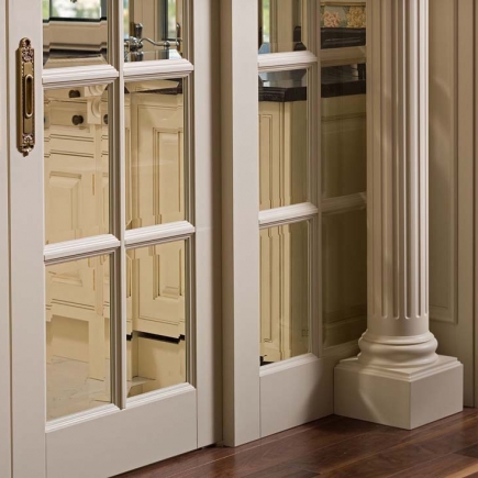 Detail of mirrored glass-paneled door beside a fluted column base