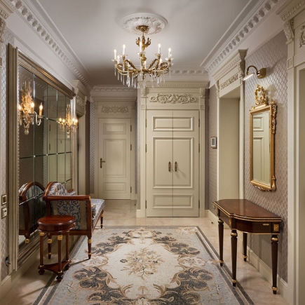 Entry hallway with a decorative mosaic rug, chandelier, and carved built-in cabinetry