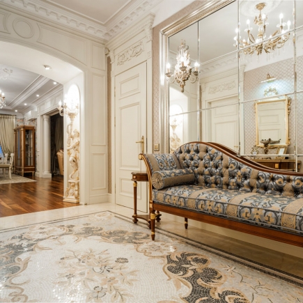 Entry hallway with a tufted chaise lounge reflected in a mirrored wall