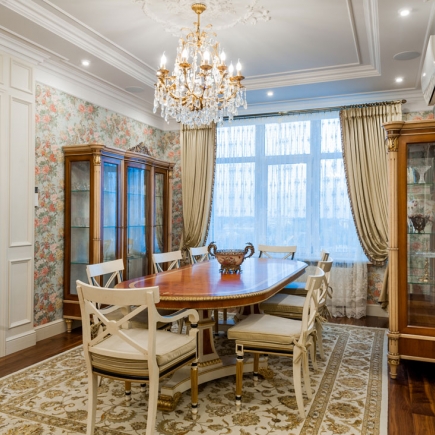 Formal dining room with oval table, crystal chandelier, and matching display cabinets