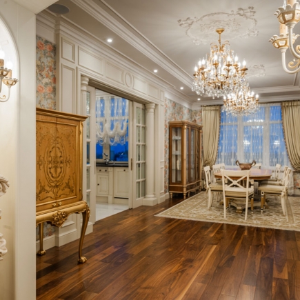 Foyer with a carved wood cabinet, crystal chandeliers, and a dining room visible beyond