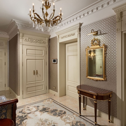 Hallway with carved built-in cabinetry, gilt-framed mirror, and console table