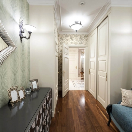 Hallway with wall sconce, floral wallpaper, and built-in closets leading to the bedrooms