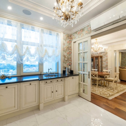 Kitchen counter beside sheer curtains overlooking the city, with a pocket door open to the dining room