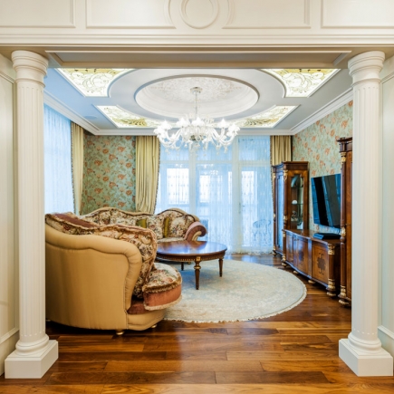 Living room framed by columns with a domed stained-glass ceiling and floral upholstered sofas