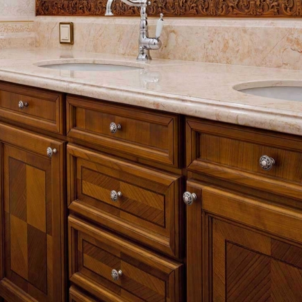 Marble double-sink vanity detail with ornate carved wood cabinetry