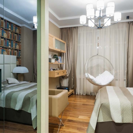 Mirrored closet door reflecting a bedroom beside a built-in desk and hanging bubble chair
