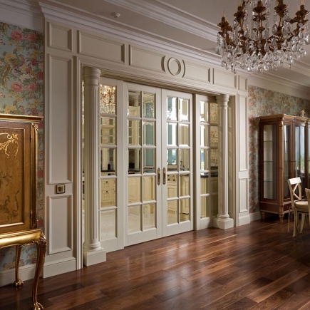 Mirrored French doors framed by fluted columns, opening onto a kitchen