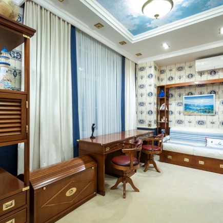 Nautical-themed bedroom with a built-in daybed, desk, and sailboat artwork