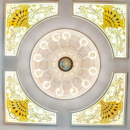 Overhead view of a stained-glass ceiling medallion with a crystal chandelier
