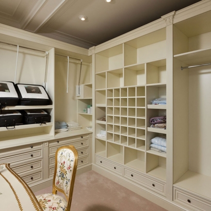 Walk-in closet with built-in cubbies, shelving, and a floral upholstered chair