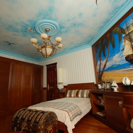 Boy's pirate-themed bedroom with a treasure chest at the foot of the bed and a tall-ship wall mural