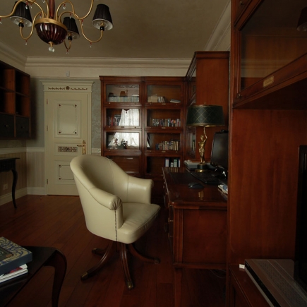 Bronze figurine lamp against damask wallpaper beside the office sofa