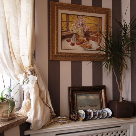 Master bedroom suite with a silk-draped window, an armchair and a bench at the foot of the bed