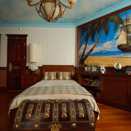 Porcelain figurines of napping children and a model sailboat on a wooden desk