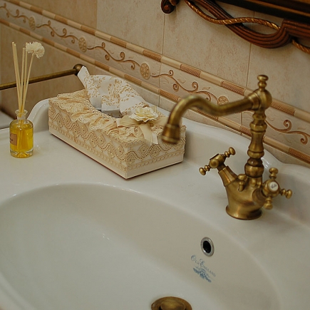 Sink close-up with a vintage brass faucet and a reed diffuser