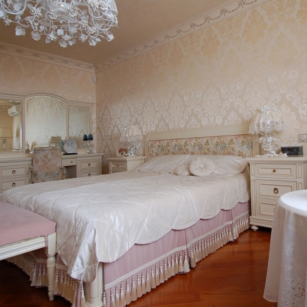 Striped-wall corner with framed still-life paintings, decorative plates and an orchid above a radiator cover