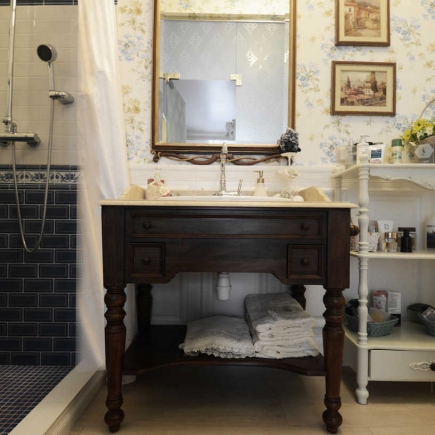 Bathroom with a dark wood vanity, gilt mirror, walk-in shower, and floral wallpaper