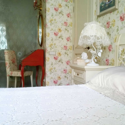 Bedroom corner with a red writing desk reflected in an oval mirror, floral wallpaper