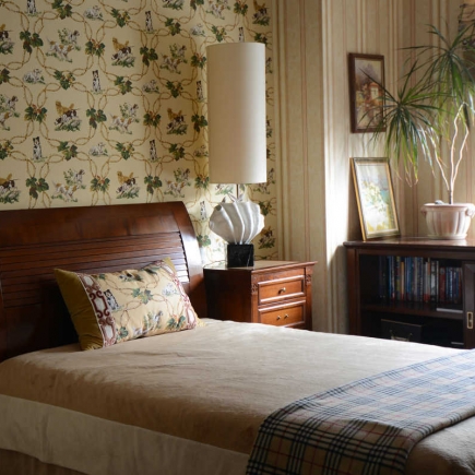Bedroom with floral wallpaper, a dark wood sleigh bed, and a potted plant on the dresser
