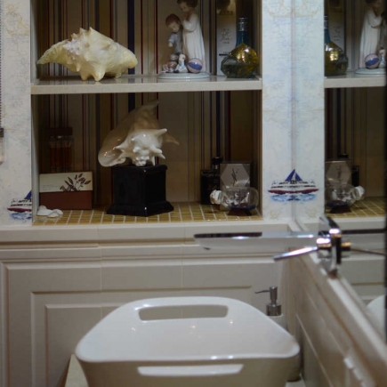 Close-up of decorative seashells and porcelain figurines on a bathroom display shelf