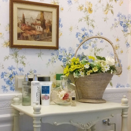 Close-up of skincare products and a floral basket on a bathroom console table