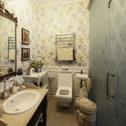 Damask-print reading nook with a wall-mounted display shelf and dark console table