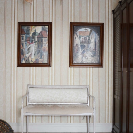 Hallway with striped wallpaper, framed cityscape paintings, and an upholstered bench
