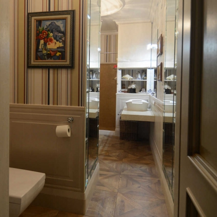 Mirrored hallway leading to a marble-tiled bathroom with herringbone floor