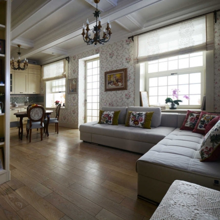 Open living room and kitchen with sectional sofa, floral wallpaper, and beamed ceiling