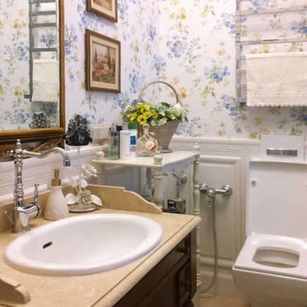 Powder room vanity with floral wallpaper, a flower basket, and framed landscape paintings