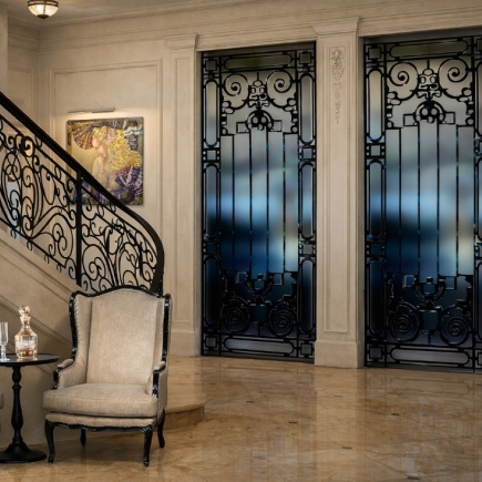 Entry hall with a wrought-iron staircase railing and matching decorative iron elevator doors