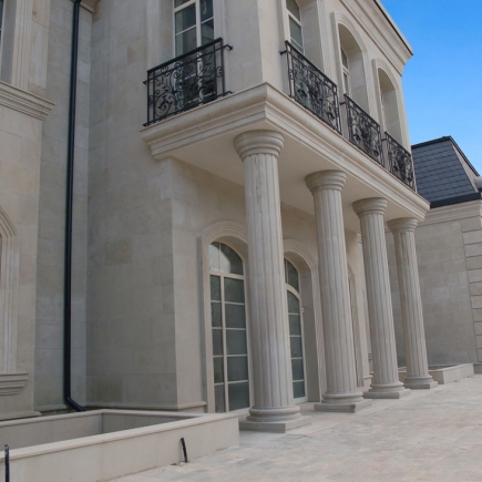 Facade detail with fluted stone columns supporting a wrought-iron balcony