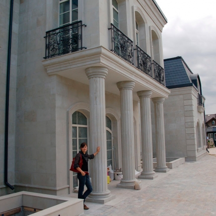 Fluted stone columns under construction, with a team member walking past the unfinished facade