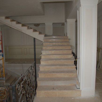 Marble staircase under construction with protective wrapping and wrought-iron railing