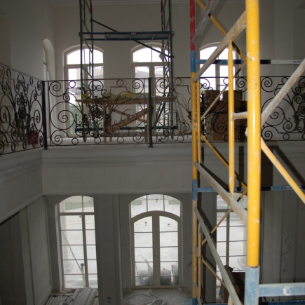 Overhead view of the double-height stairwell with wrought-iron balcony railings and scaffolding