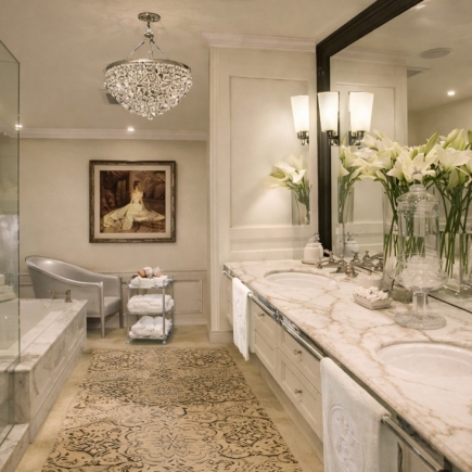 Primary bathroom with a freestanding tub, crystal chandelier, and marble double vanity