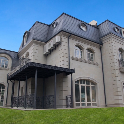 Rear exterior with a covered wrought-iron balcony and arched ground-floor windows