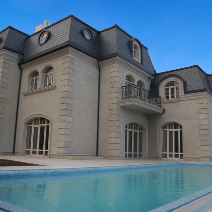 Rear exterior with slate mansard roof and infinity-edge pool