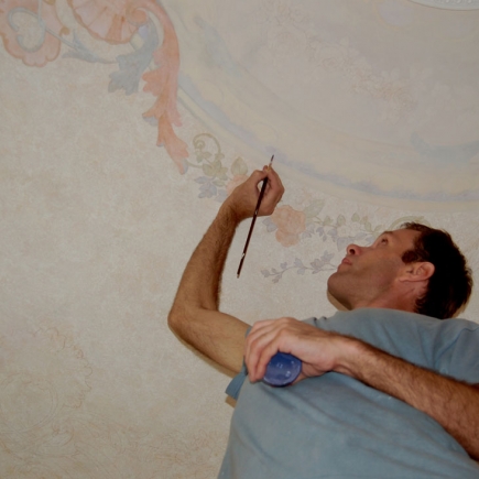 Artisan hand-painting the floral fresco ceiling