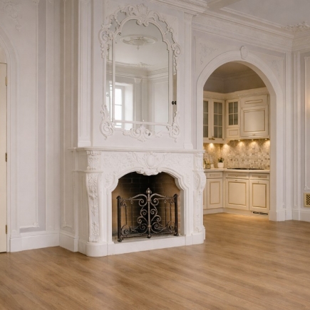 Carved marble fireplace with wrought iron screen, framed by an arched kitchen doorway